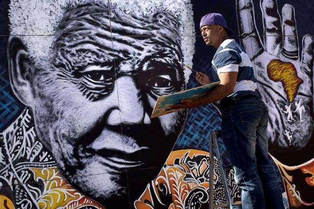 South African artist John Adams works on a giant acrylic-on-canvas painting of Nelson Mandela in the driveway of his house in a suburb of Johannesburg, South Africa