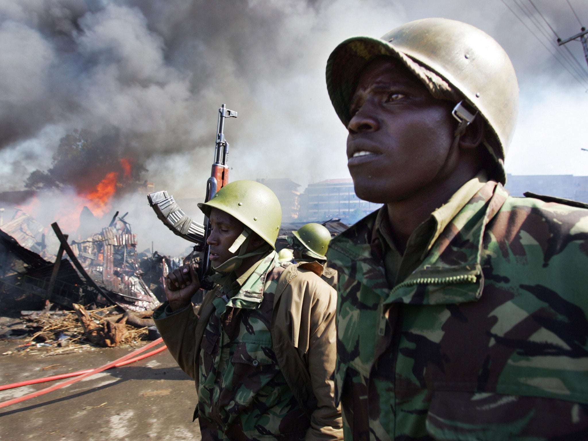 Kenyan police walk past burning shacks in the Mathare Slum 30 December 2007 in Nairobi