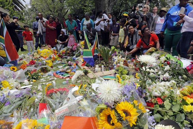 Mourners lay flowers outside the house of the late South African president Nelson Mandela in Johannesburg