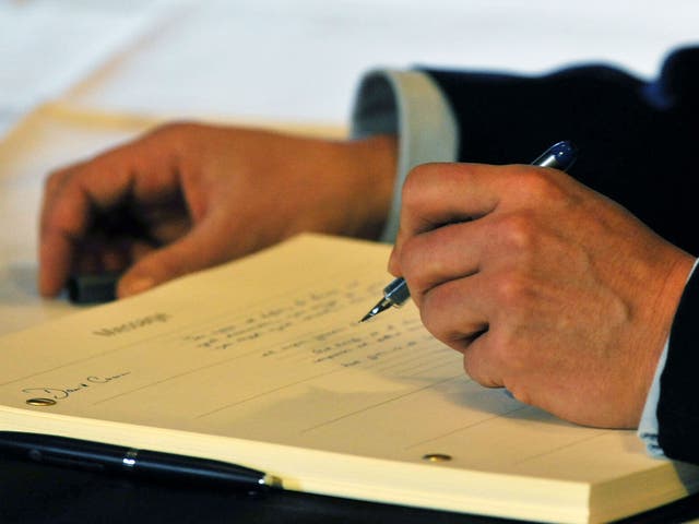 Britain's Prime Minister David Cameron signs the book of condolence at the South African Embassy in central London