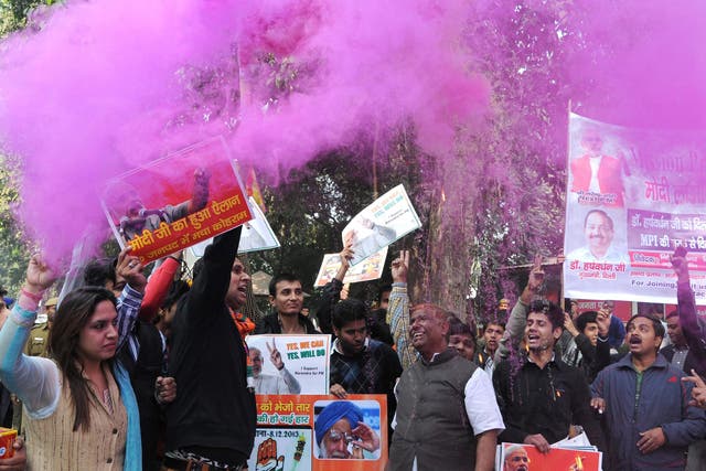 Supporters of the Indian Bharatiya Janata Party (BJP) spray color dust as they celebrate outside their party headquarter after the announcement of the results of the Assembly elections