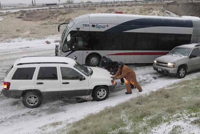 Motorists try to get vehicles and a jack-knifed city bus up an icy hill on East Lancaster Ave. in Fort Worth, Texas