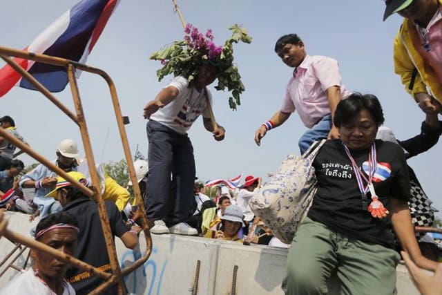 Anti-government protesters jump over a concrete barricade as they get closer to the Government House in Bangkok today