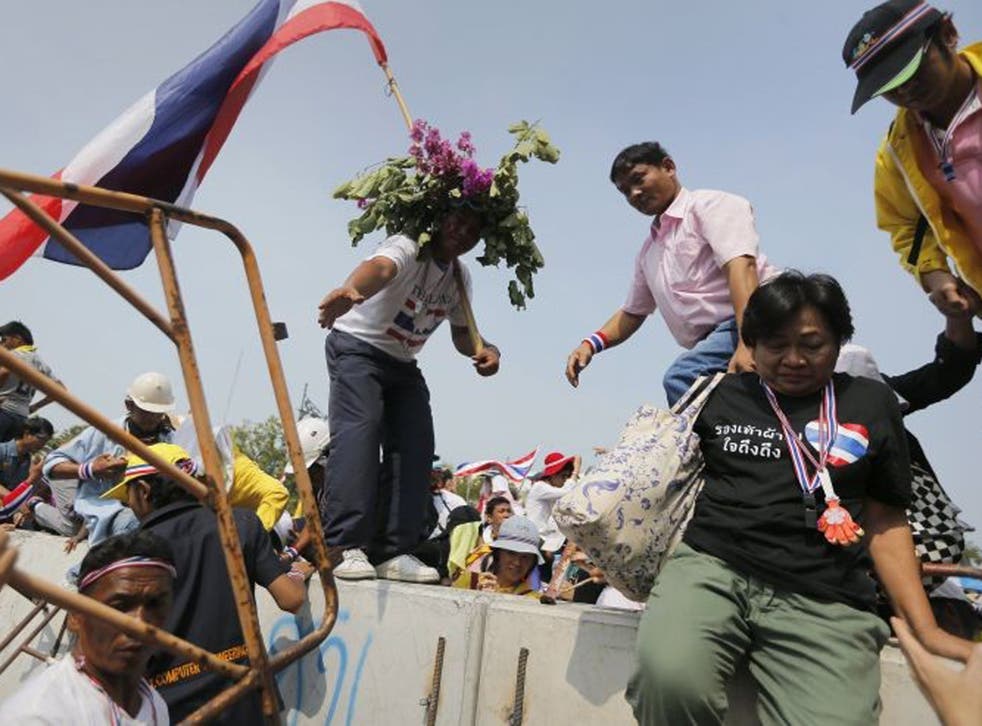 Anti-government protesters jump over a concrete barricade as they get closer to the Government House in Bangkok today