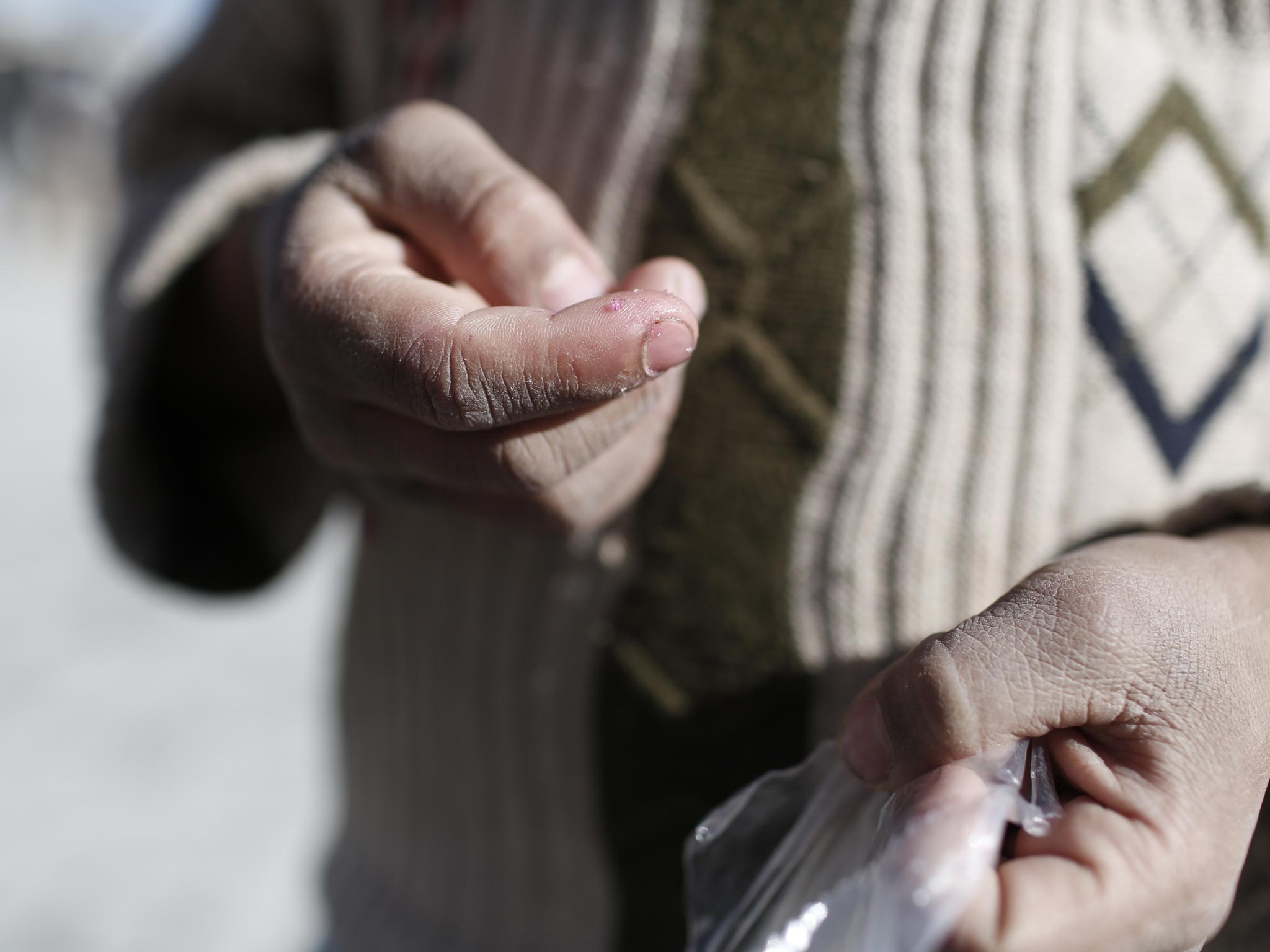 Seven year old Muhammad eats sweets outside a shop at the 'Container City' refugee camp