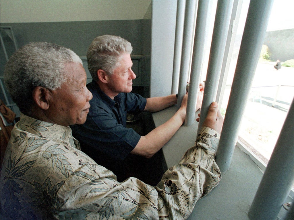 Mandela and former US president Bill Clinton look outside from Mandela's Robben Island prison cell, in 1998