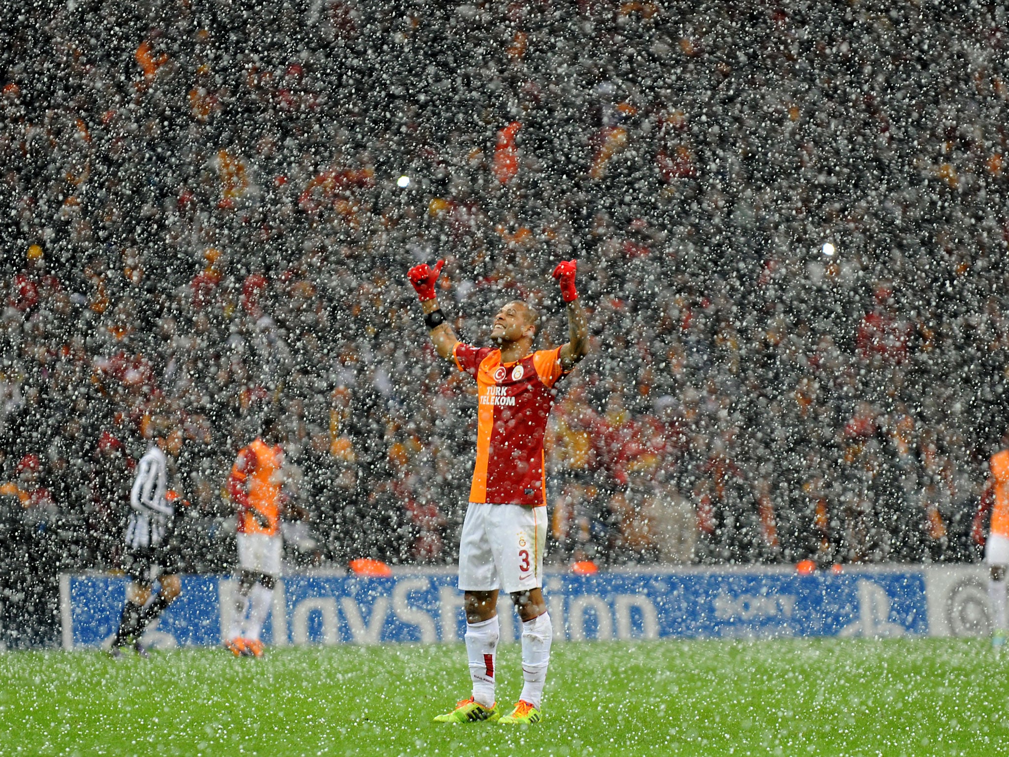 Galatasaray midfielder Felipe Melo raises his arms as the snow falls in Istanbul