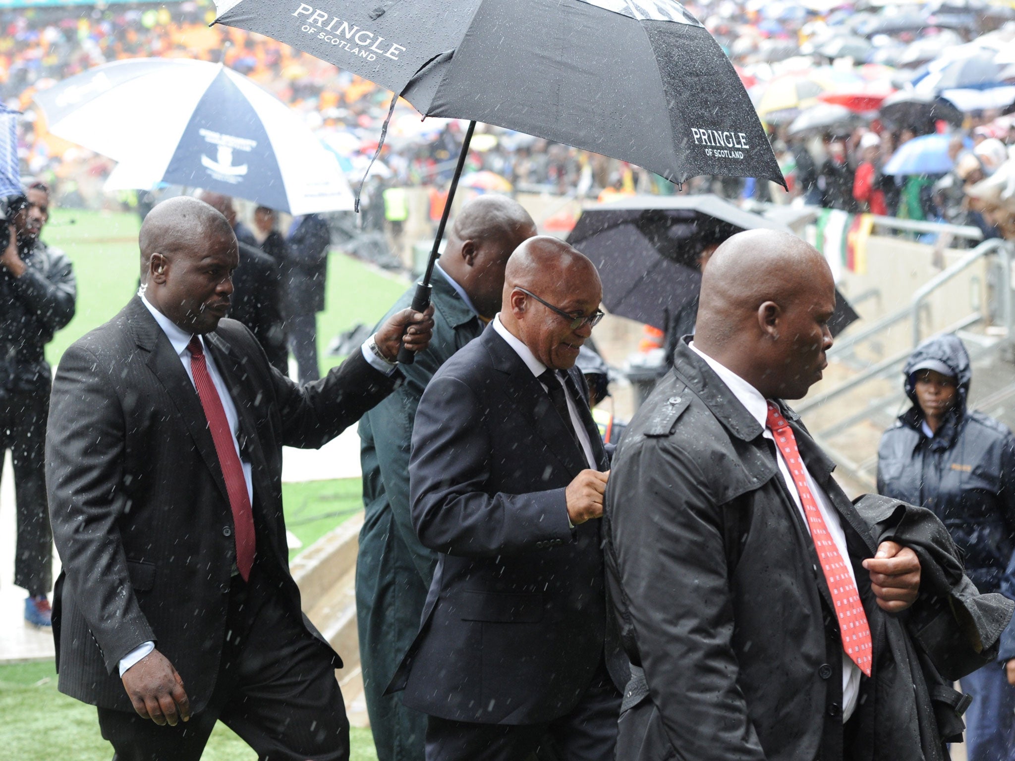 President Jacob Zuma, centre, arrives for Nelson Mandela's memorial service at the rainswept FNB Stadium (AFP)