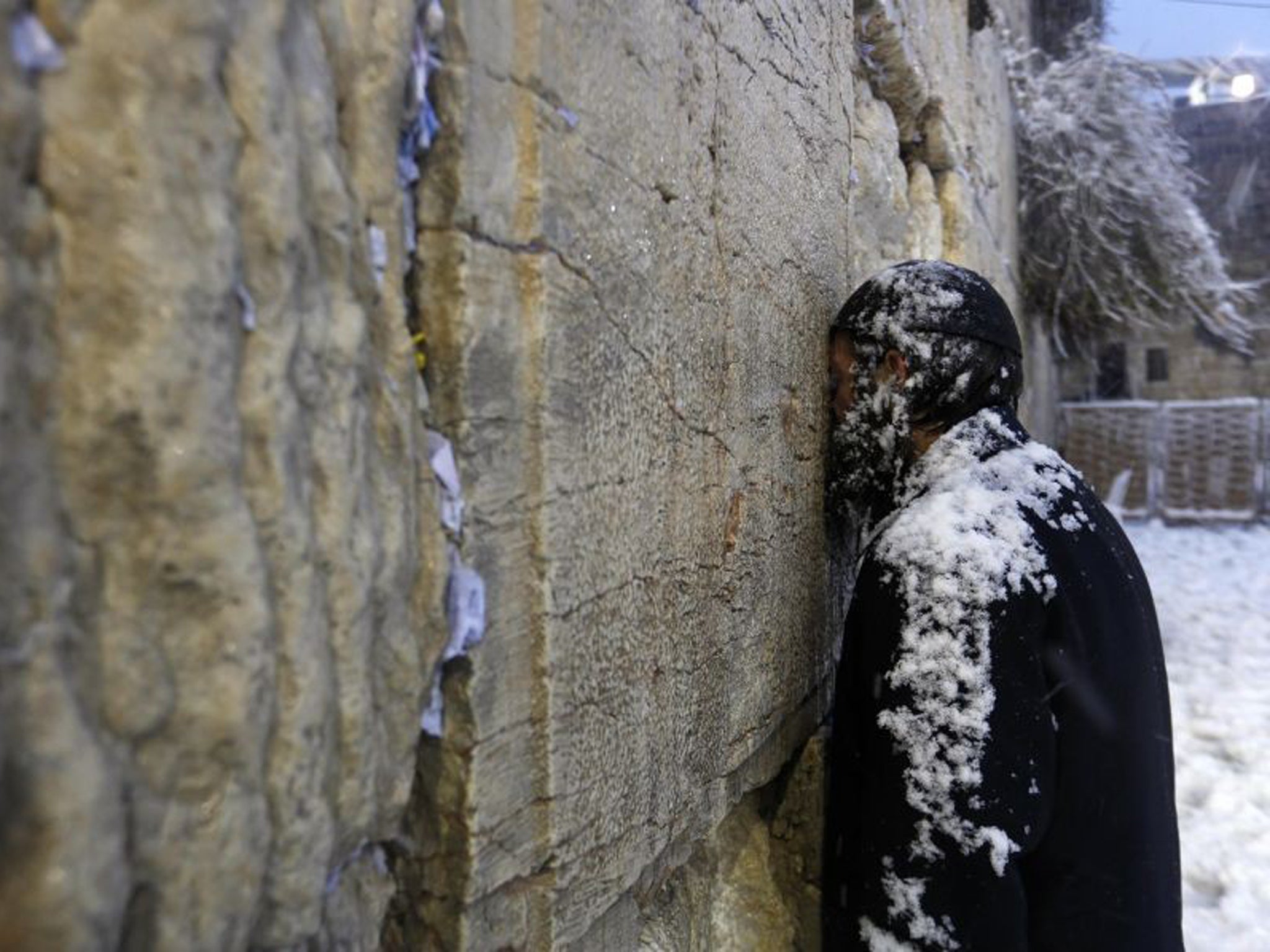 An Ultra-Orthodox Jewish man prays at the Western Wall in Jerusalem's Old City during a snowstorm on 13 December 2013