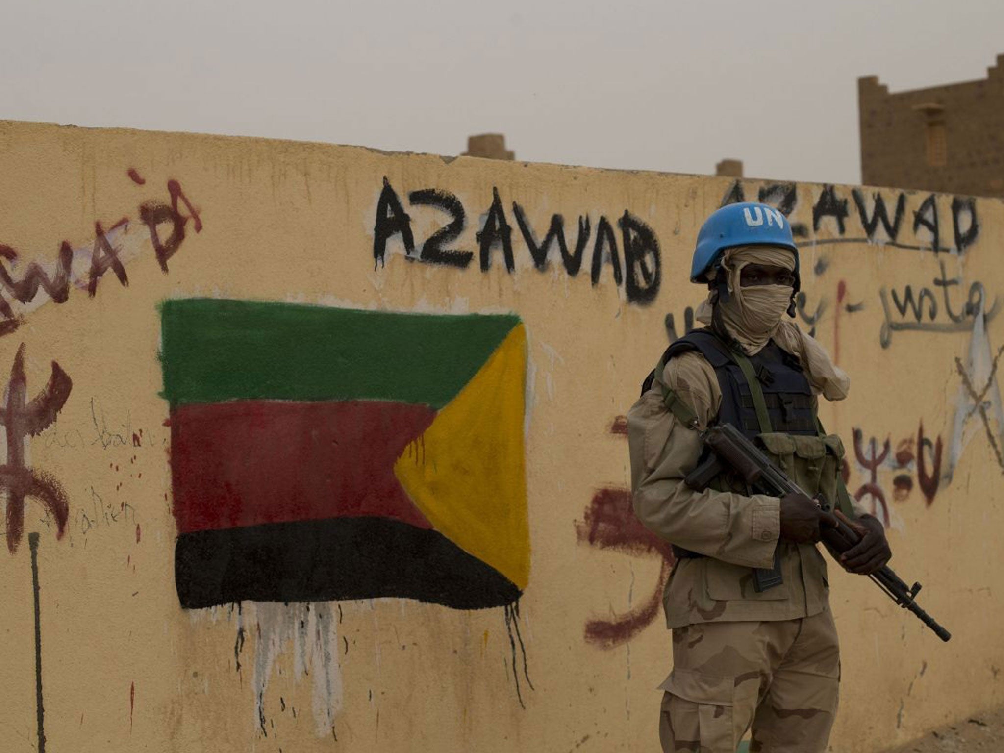 In this Sunday, July, 28, 2013 file photo, a United Nations peacekeeper stands guard at the entrance to a polling station covered in separatist flags and graffiti supporting the creation of the independent state of Azawad, in Kidal, Mali
