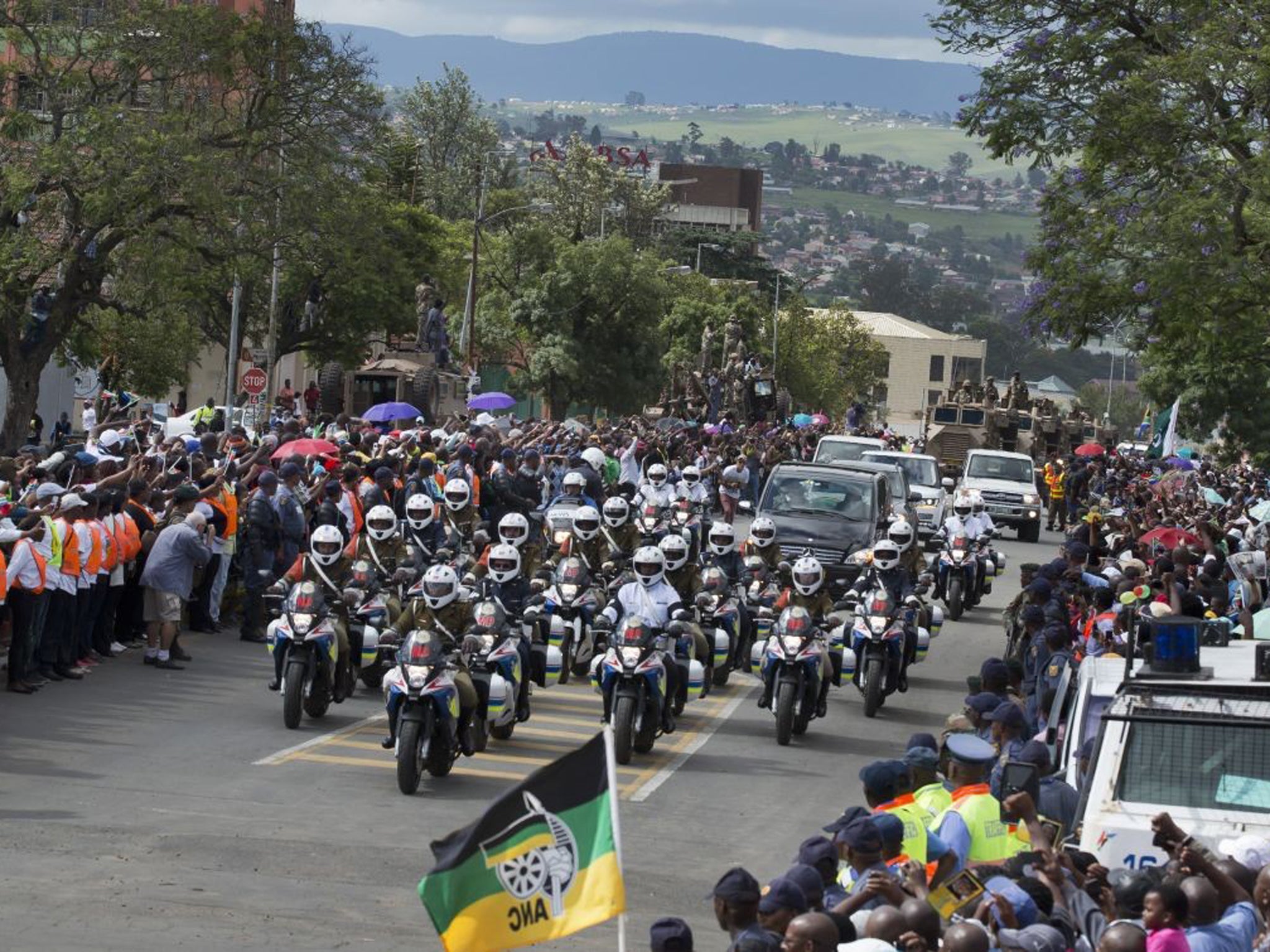The motorcade transporting the body of Nelson Mandela, in black hearse, passes through crowds of mourners gathered in the town of Mthatha on its way to Qunu