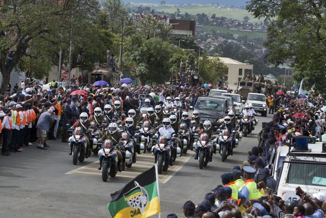 The motorcade transporting the body of Nelson Mandela, in black hearse, passes through crowds of mourners gathered in the town of Mthatha on its way to Qunu