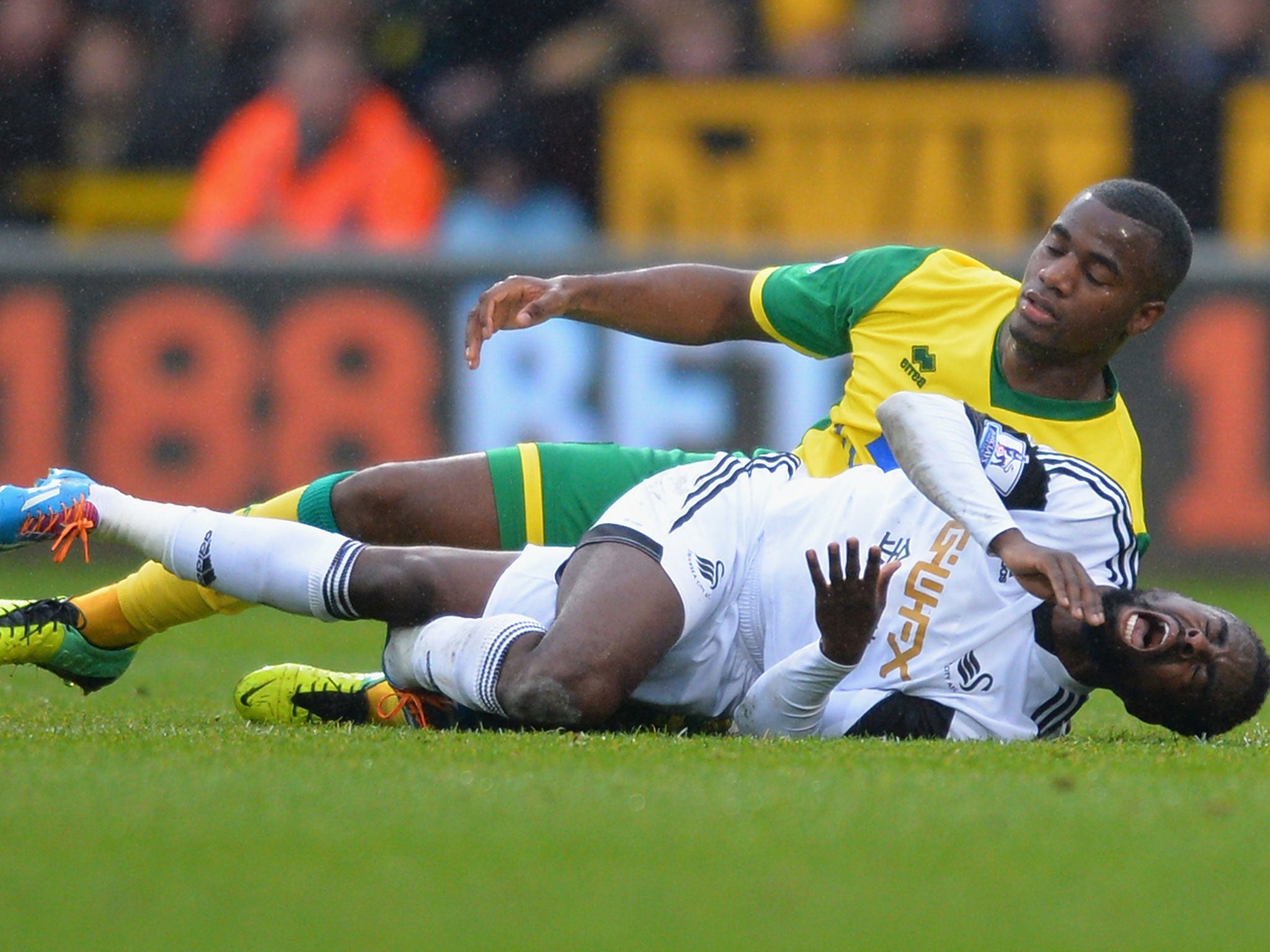 Nathan Dyer screams out in pain after landing awkwardly when competing with Sebastian Bassong for the ball