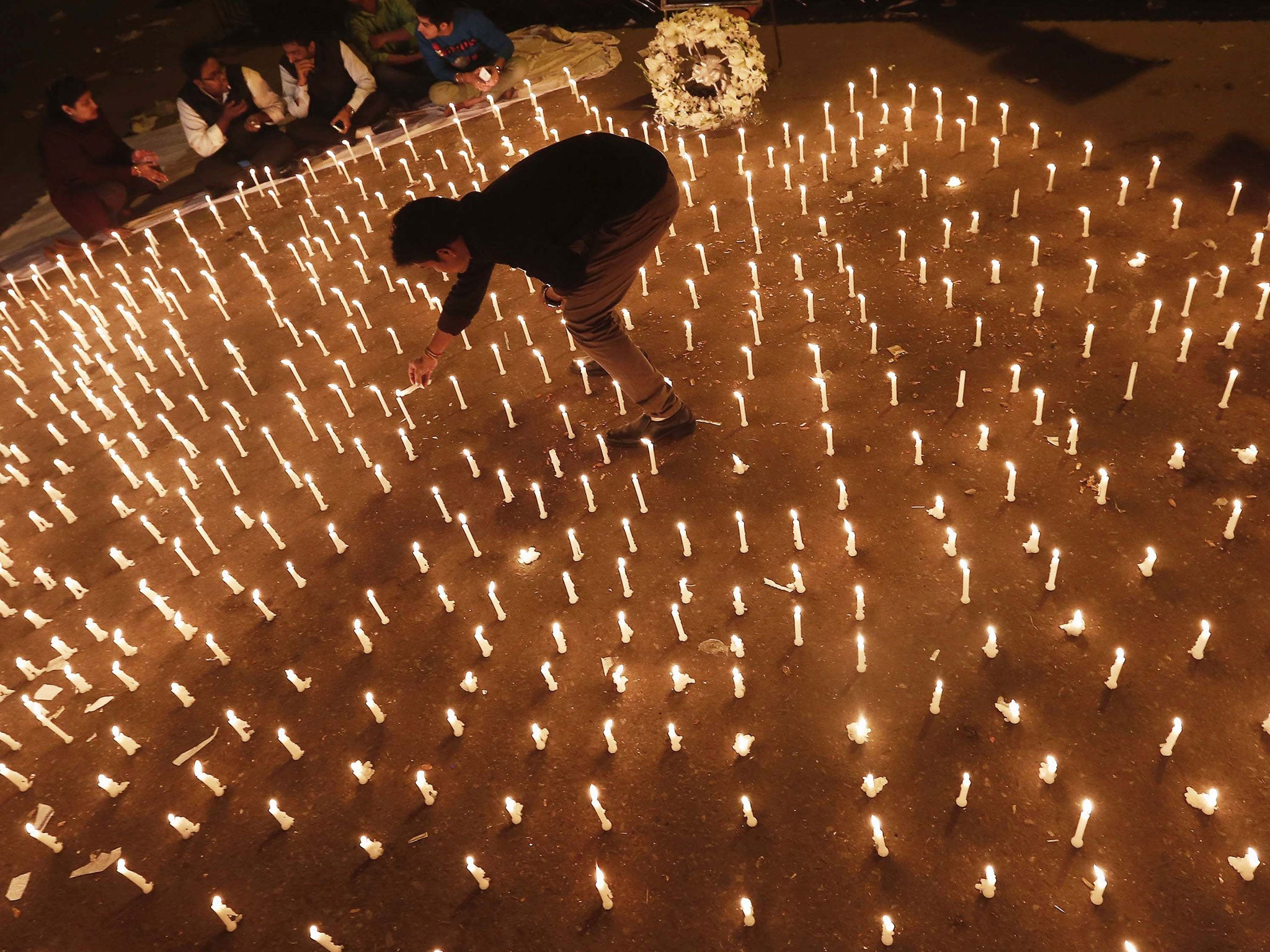 A protester lights candles during a candlelight vigil to mark the first anniversary of the Delhi gang rape