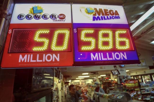 A worker at Nick's Liquor Store sells lottery tickets as a sign shows the Mega Millions jackpot estimated at $586 million in Venice, California December 16, 2013. The U.S. Mega Millions jackpot has grown to an estimated $586 million making it the second-l