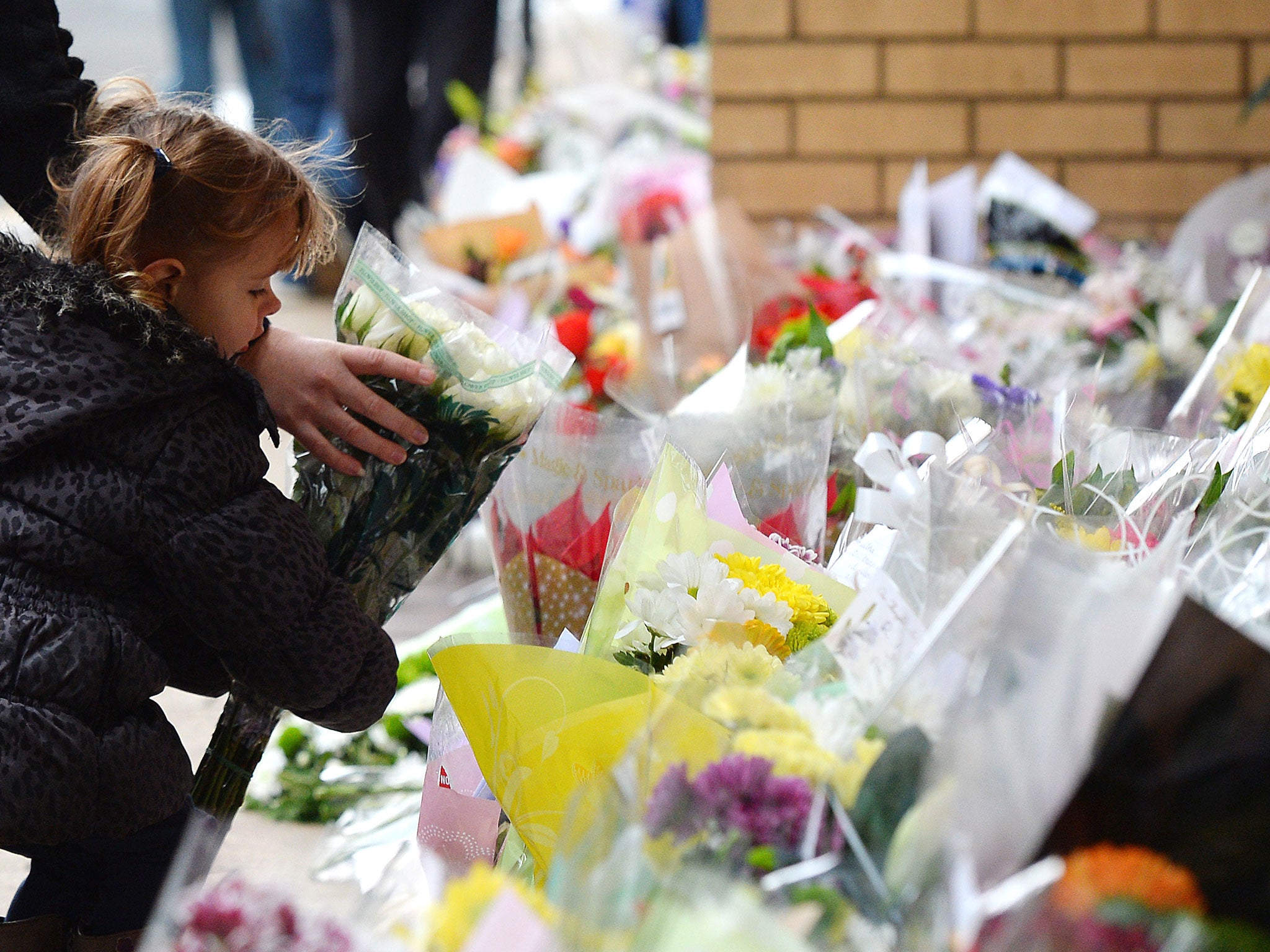 A little girl lays flowers near to the Clutha bar where a police helicopter crashed (Image: Getty)