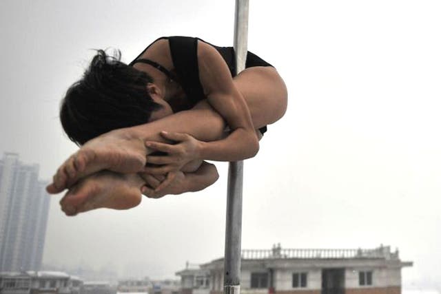 A pole dancer practices during a promotional event by members of China's national pole dancing team