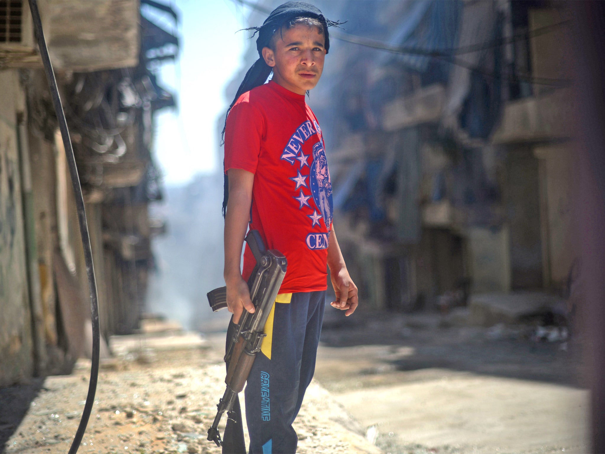 A Syrian boy holds an AK-47 assault rifle in the majority-Kurdish Sheikh Maqsud district of the northern Syrian city of Aleppo