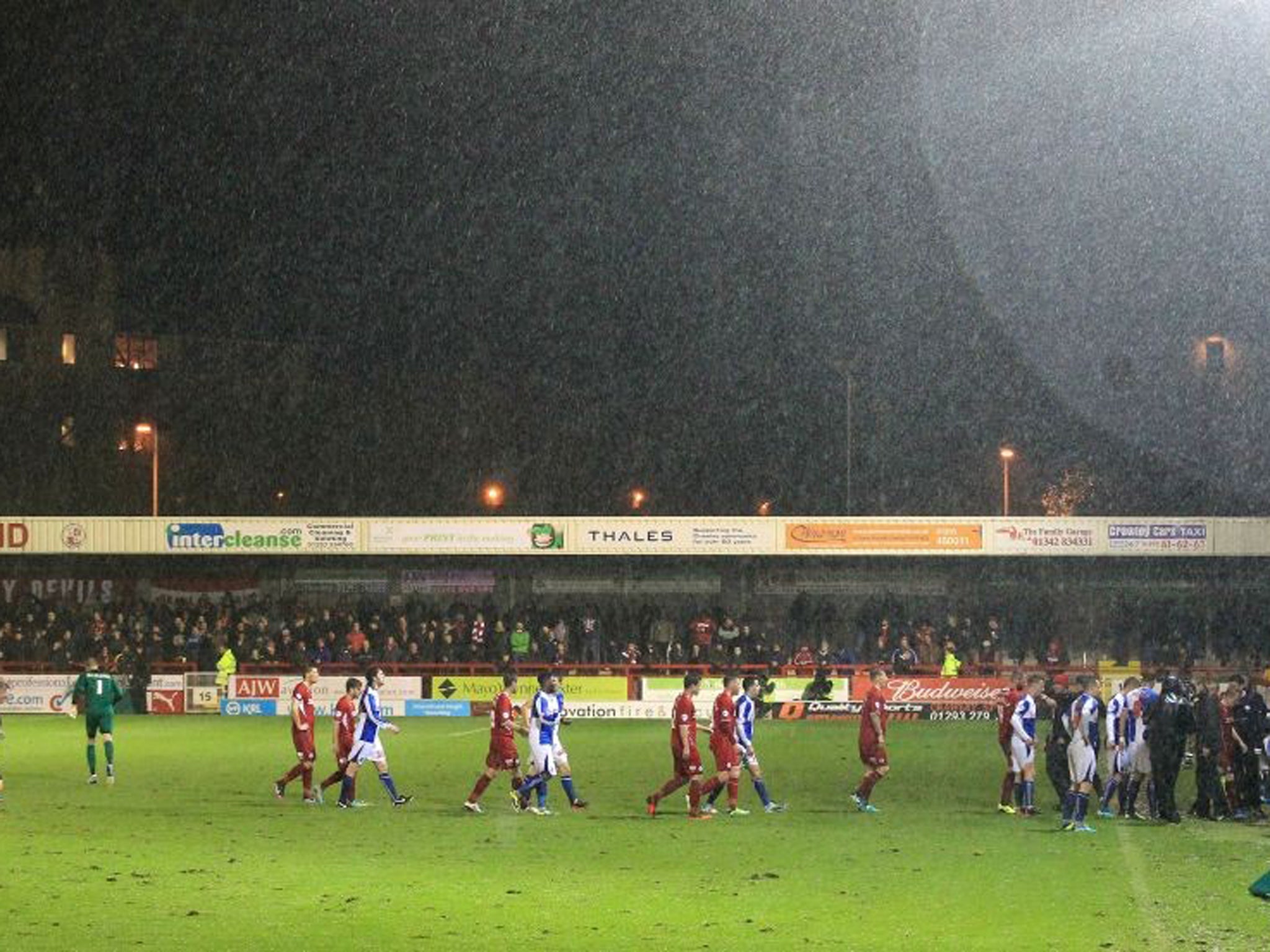 Crawley Town and Bristol Rovers players leave the pitch as the match is abandoned due to bad weather
