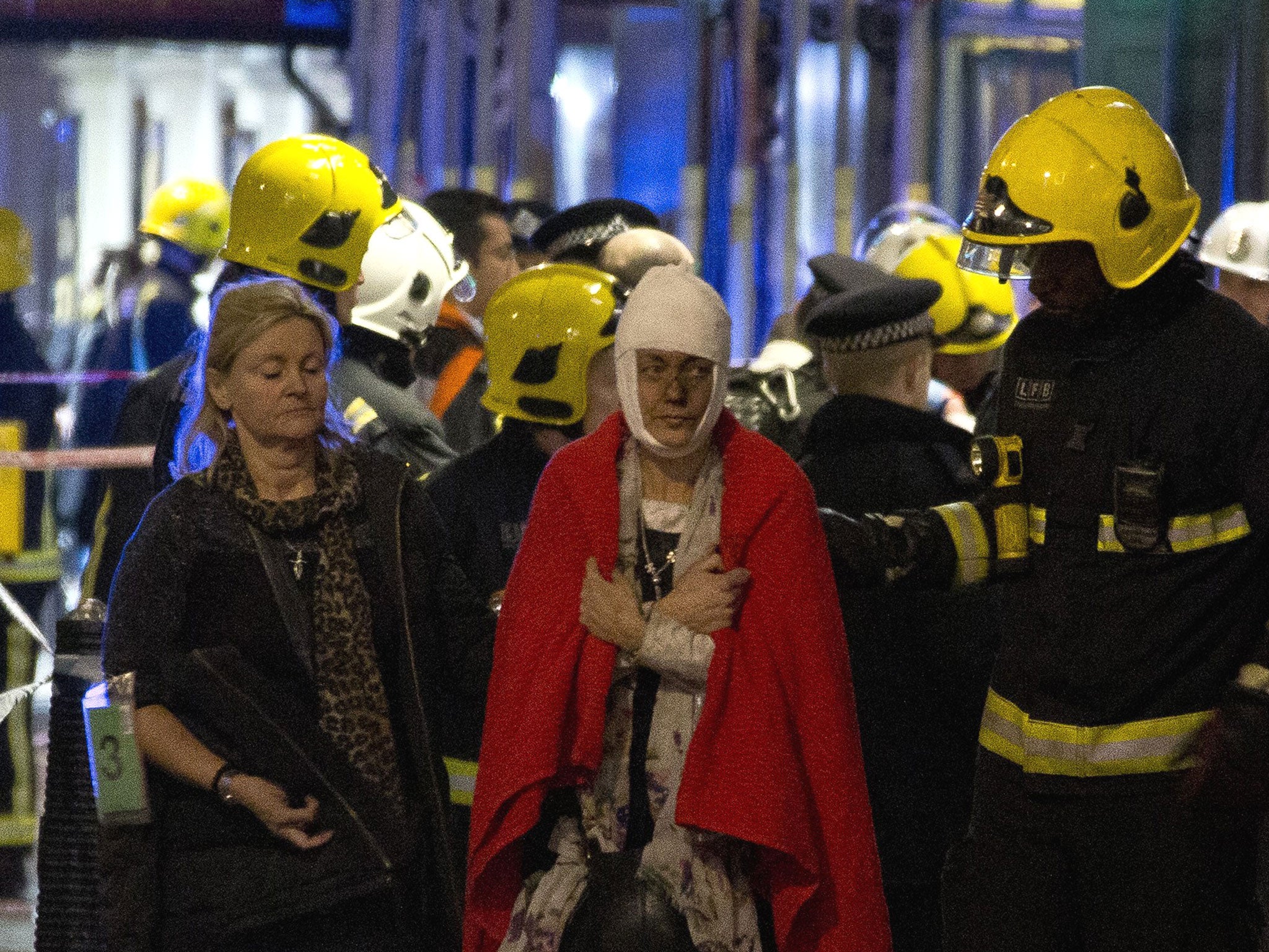 A woman walks, bandaged and wearing a blanket given by emergency services (Joel Ryan/AP)