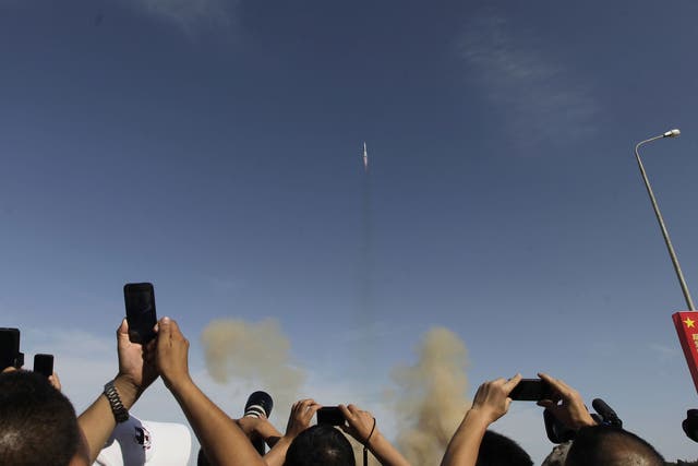 Chinese visitors take photos of the Changzheng-2F rocket with the Shenzhou-10 manned spacecraft carrying three Chinese astronauts