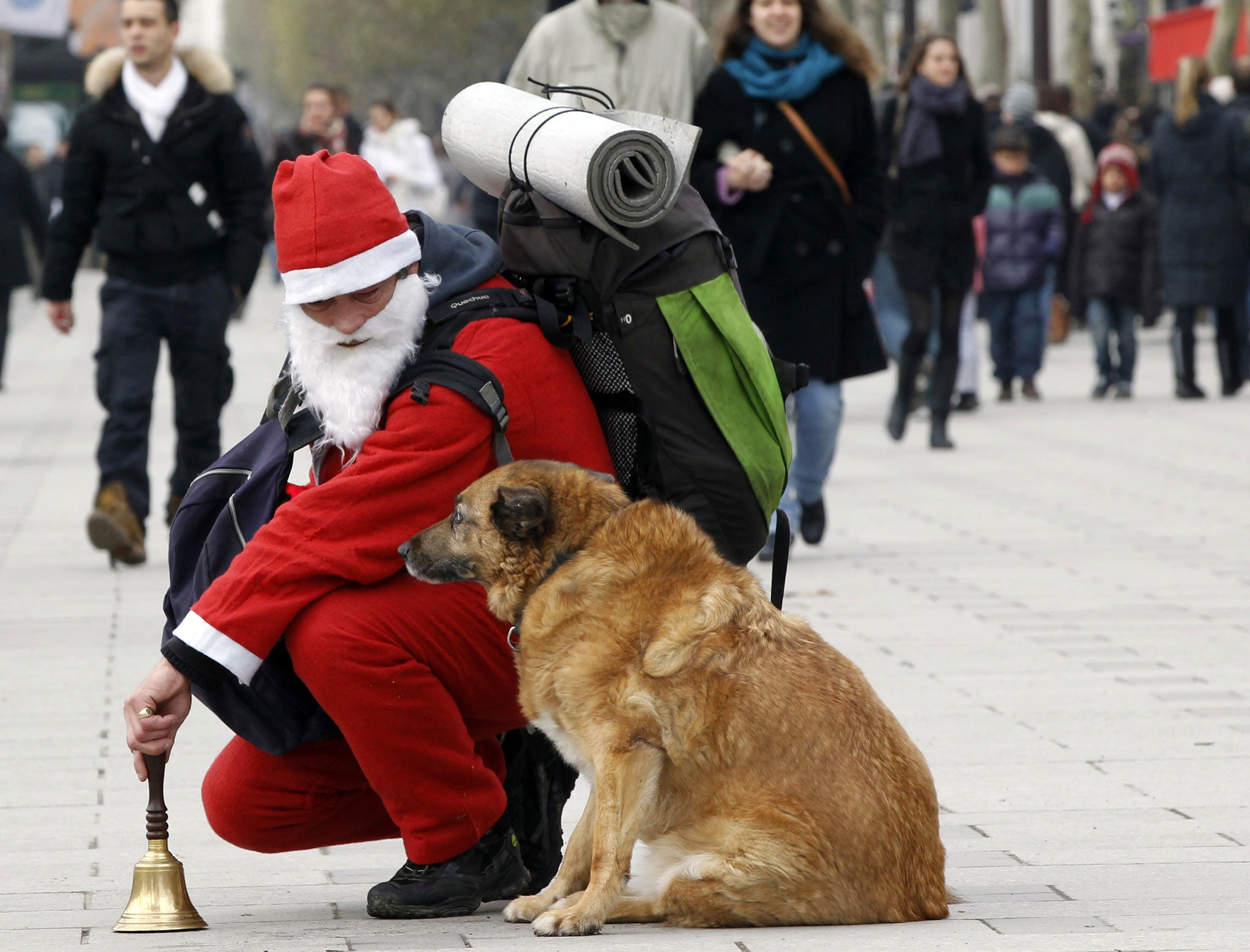 A homeless man dressed up as Santa Klaus looks at his dog in the Champs-Elysees in Paris