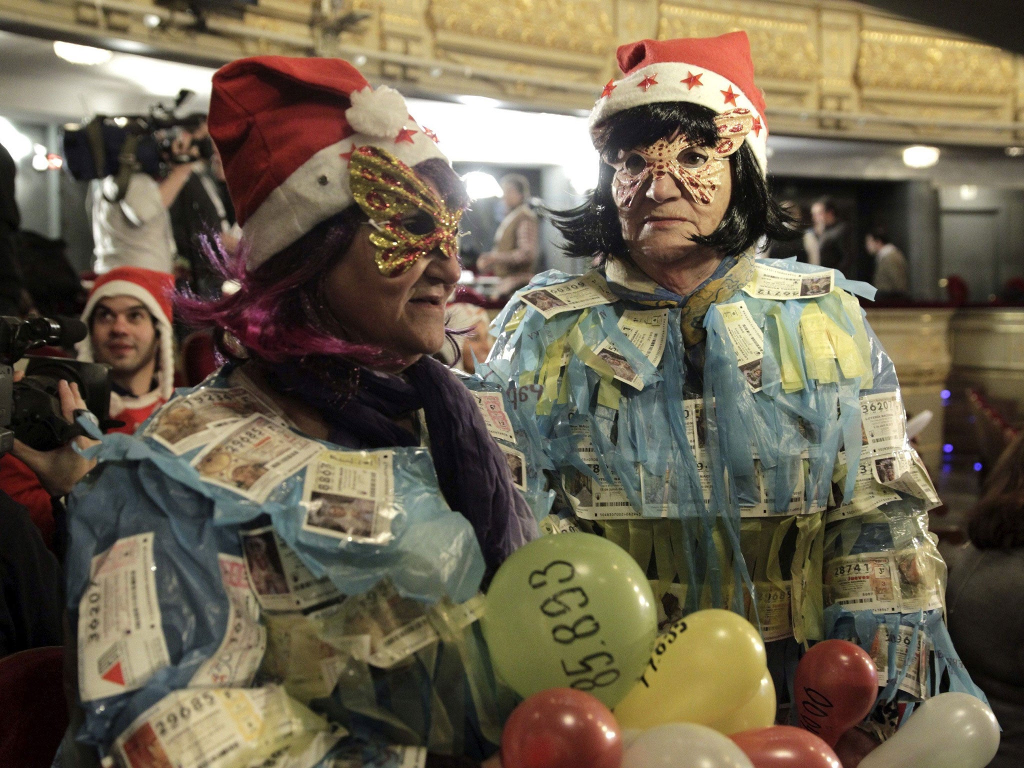 Two women display 'El Gordo' lottery tickets on their bodies as they wait for the beginning of the draw at Madrid's Teatro Real