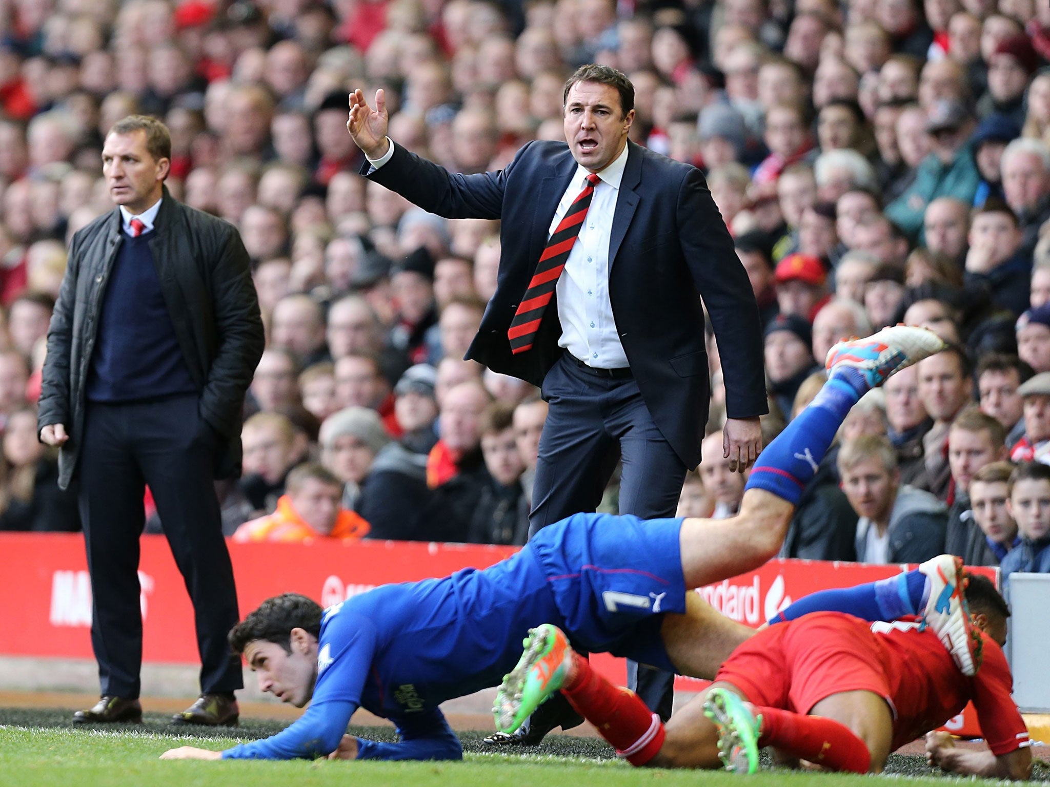 Malky Mackay, centre, who remains the Cardiff City manager, focused on his side's game at Anfield on Saturday, a 3-1 defeat, despite all the off-field distractions provided in the previous 48 hours by his club's billionaire owner, Vincent Tan