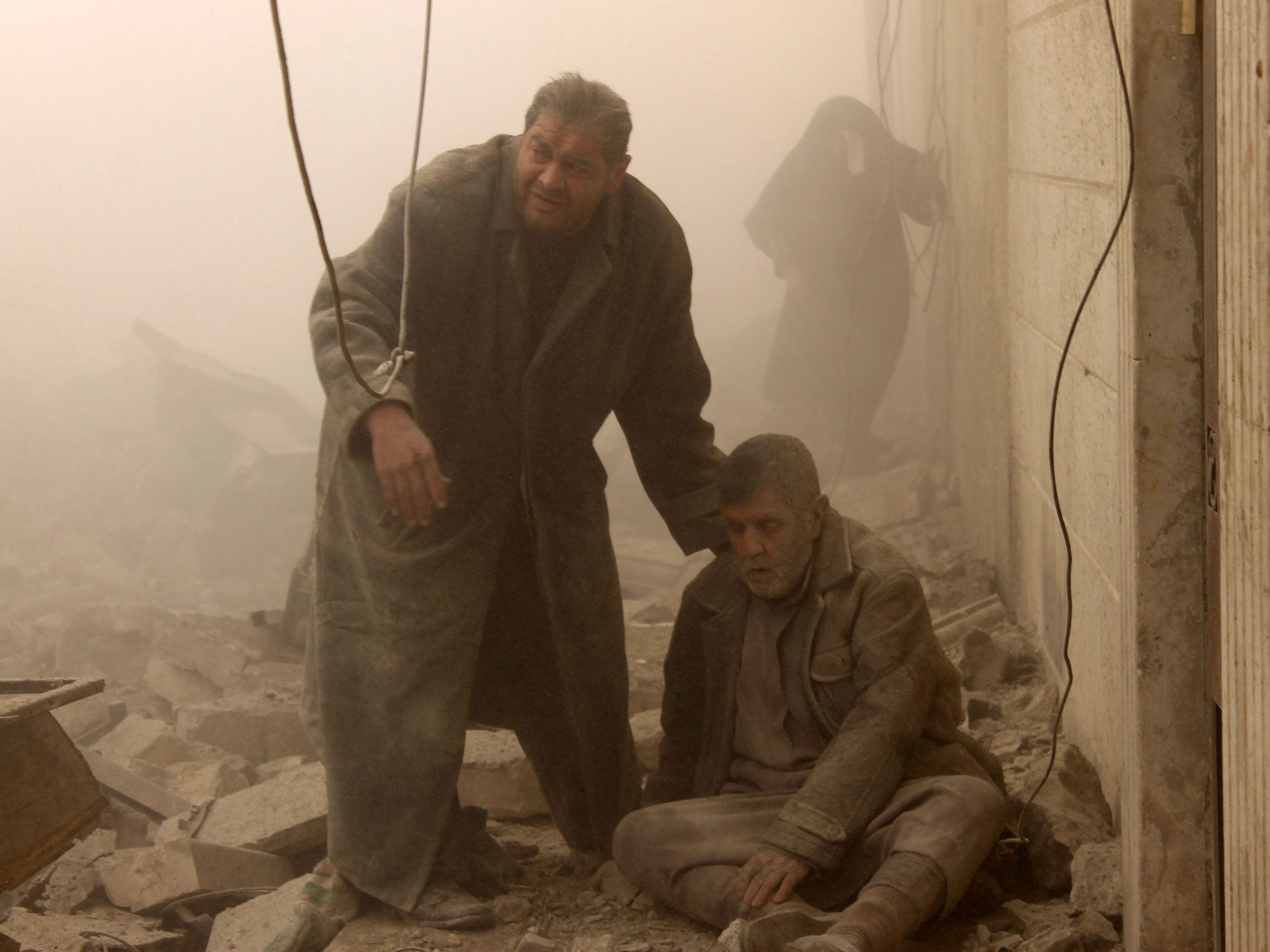 A Syrian man helps an injured man following an airstrike in Aleppo's Maadi neighborhood. Two children were among at least 13 people killed in new air strikes on a rebel-held district