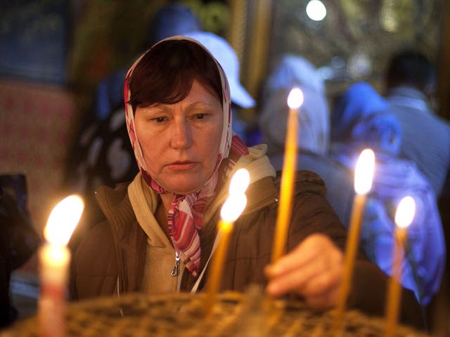 A worshipper lights candles at the Church of the Nativity 