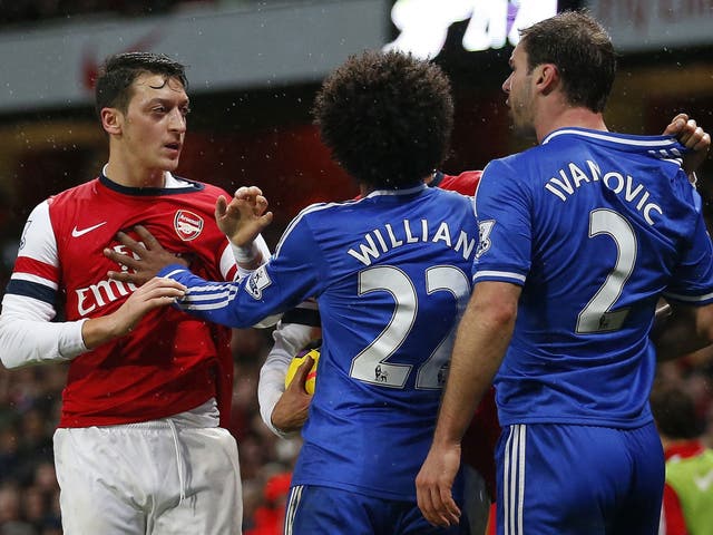 Mesut Özil (left) and Branislav Ivanovic square up during the match at the Emirates