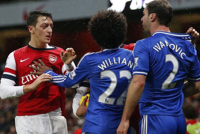 Mesut Özil (left) and Branislav Ivanovic square up during the match at the Emirates