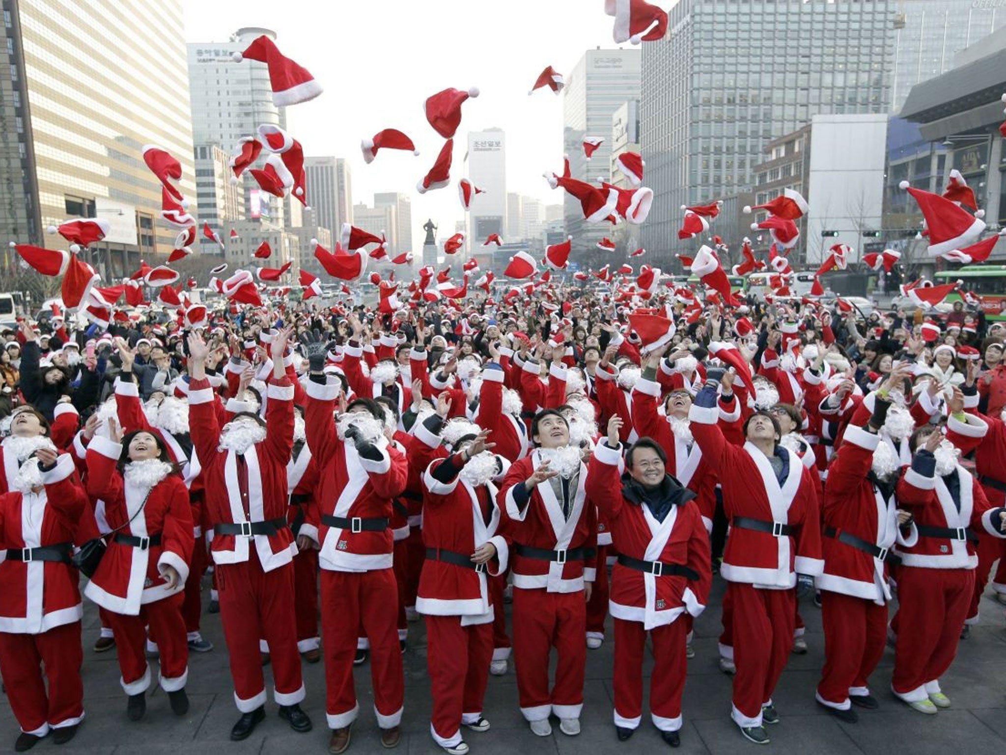 More than 1,000 volunteers clad in Santa Claus costumes throw their hats in the air as they gather to deliver gifts for the poor in downtown Seoul