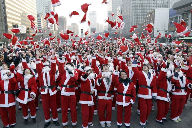 More than 1,000 volunteers clad in Santa Claus costumes throw their hats in the air as they gather to deliver gifts for the poor in downtown Seoul