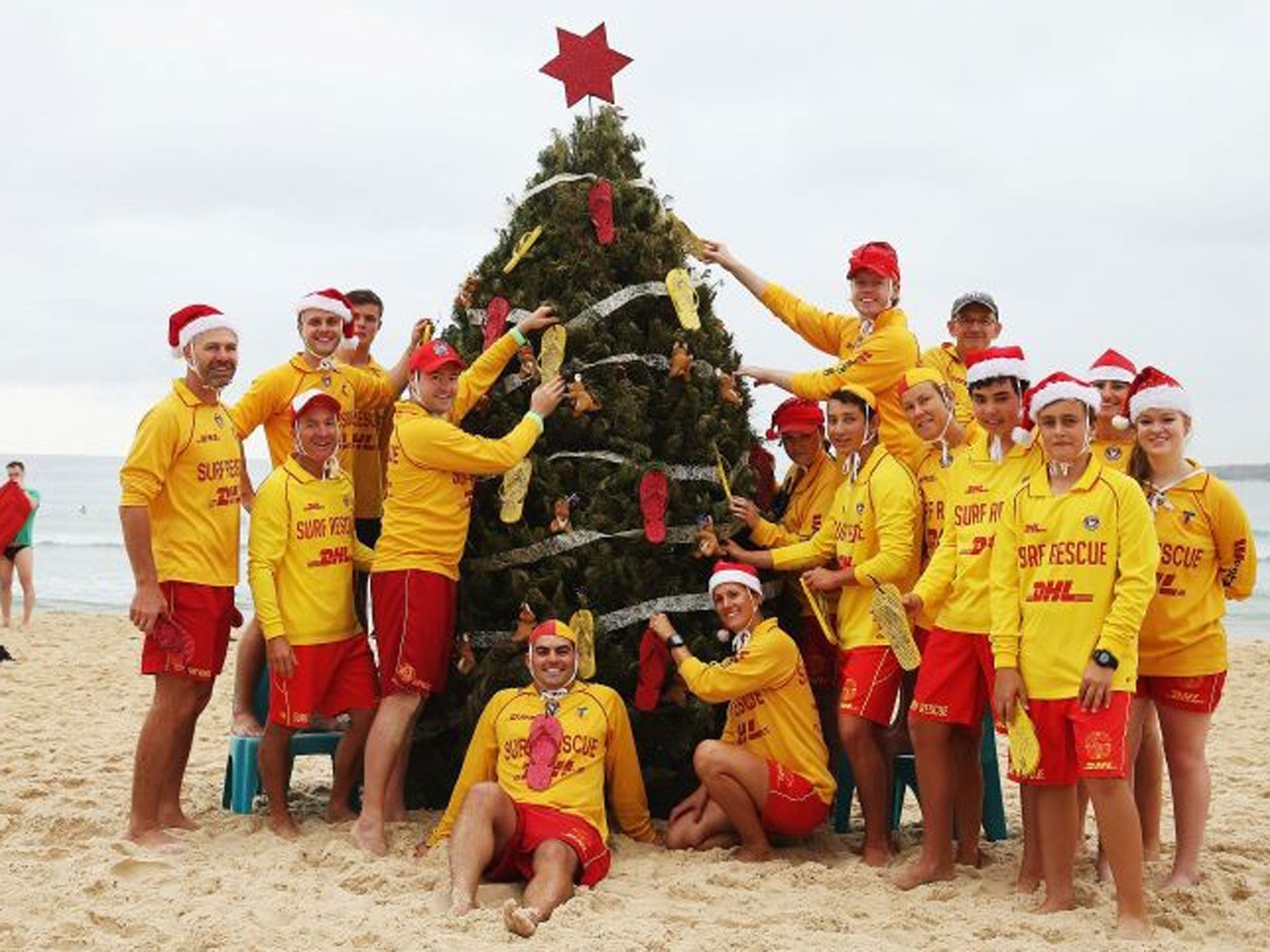 Bondi Lifeguards pose in front of their Christmas tree at Bondi Beach in Sydney
