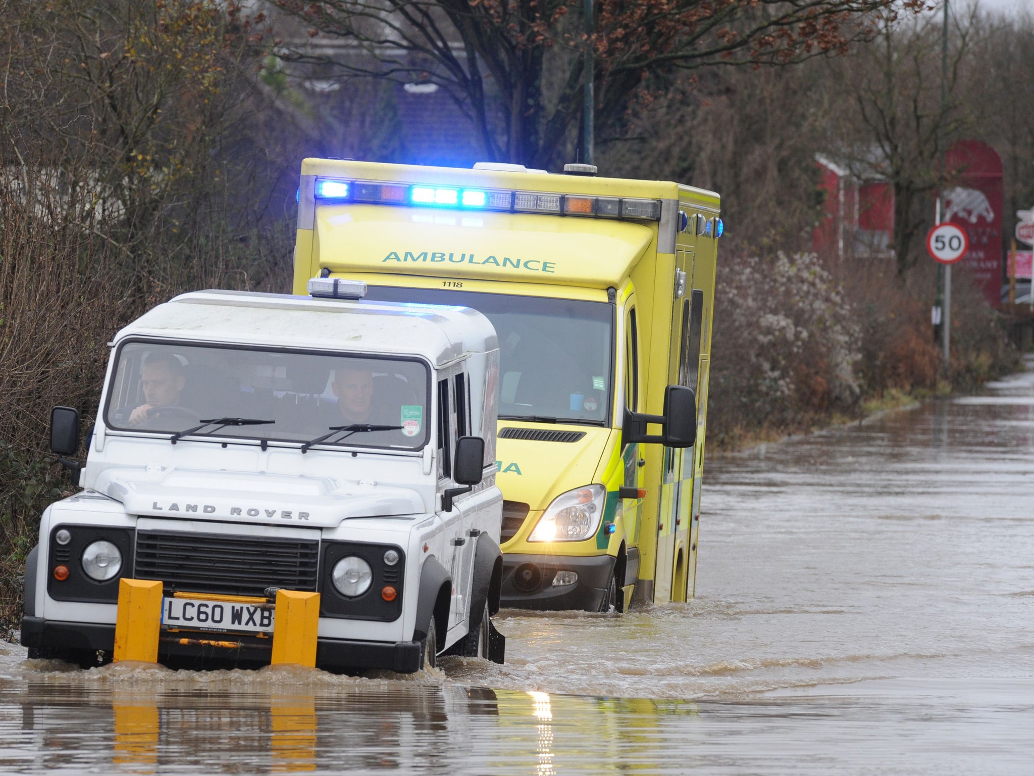 An ambulance on route to a 999 call heads into flood water at Polhill in Kent with help from men in a white jeep in front