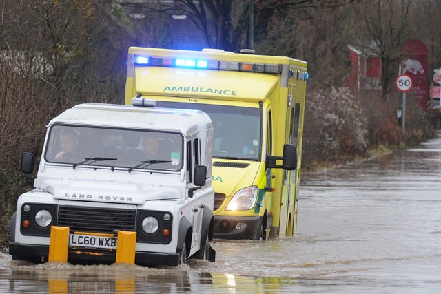 An ambulance on route to a 999 call heads into flood water at Polhill in Kent with help from men in a white jeep in front