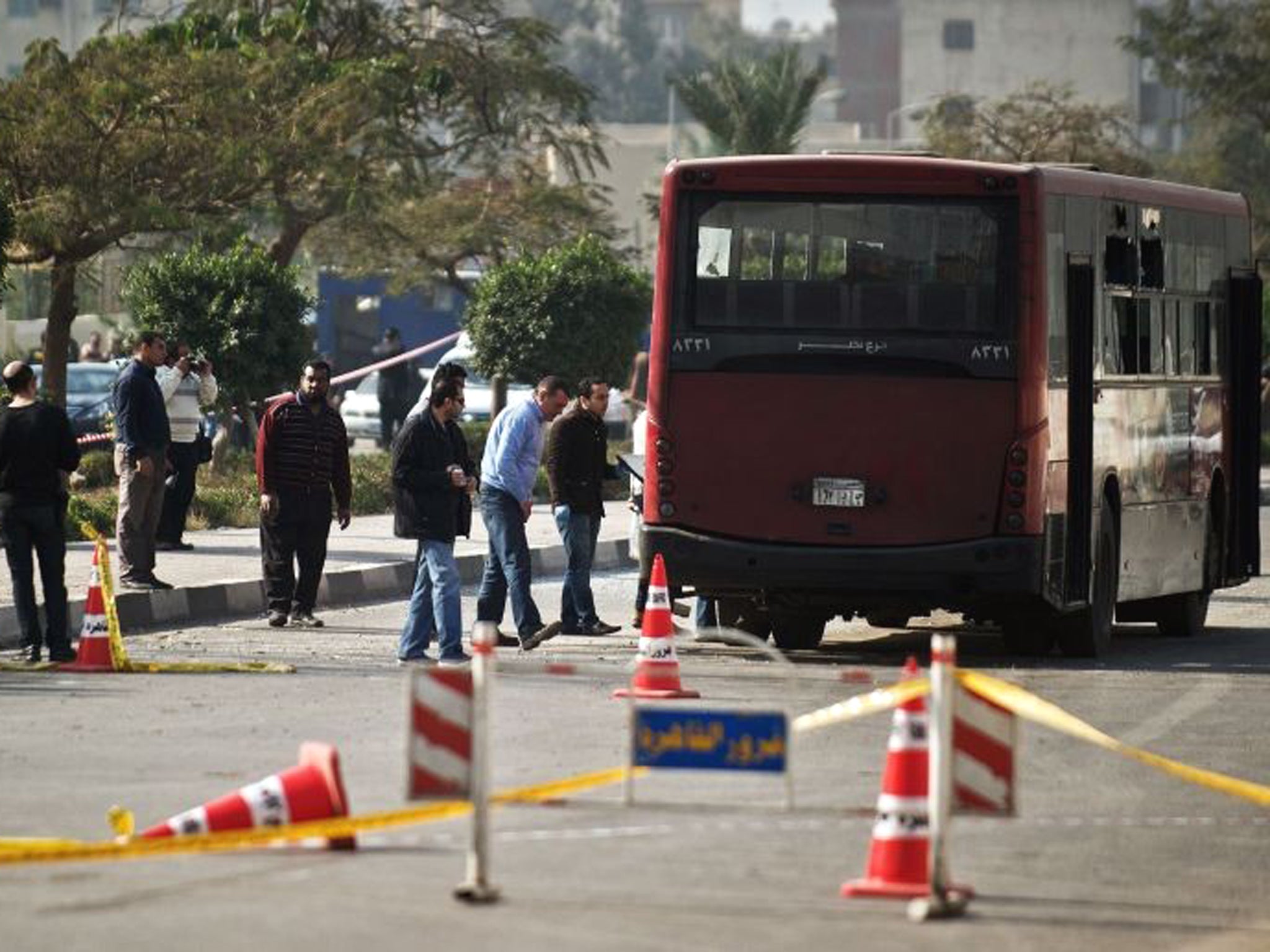 Egyptian security officials inspect the wreckage of a bus that was damaged by an explosion