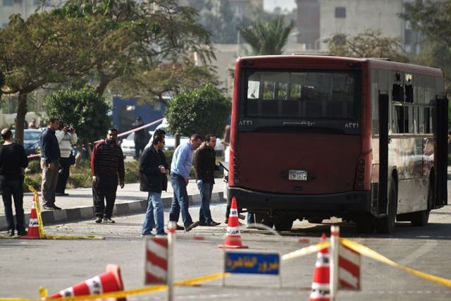 Egyptian security officials inspect the wreckage of a bus that was damaged by an explosion