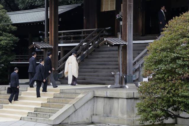 Japan's Prime Minister Shinzo Abe is led by a Shinto priest as he visits Yasukuni shrine in Tokyo 