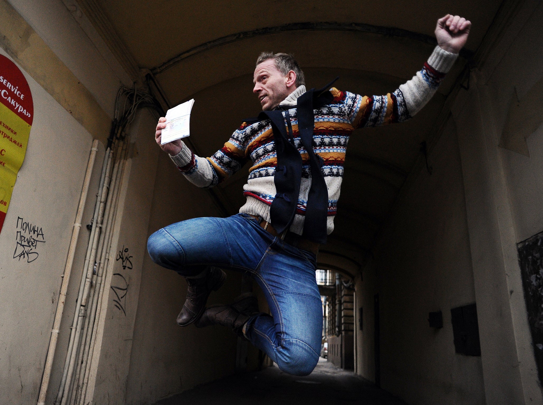 Greenpeace International activist Mannes Ubels from the Netherlands jumps for joy holding his passport outside of the offices of the Federal Migration Service Department in St. Petersburg after receiving a Russian transit visa