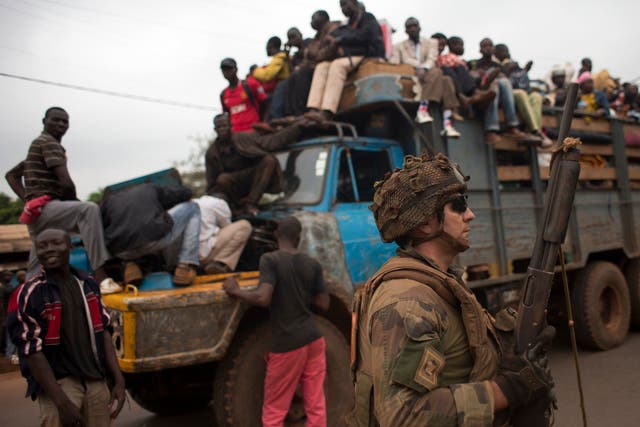 French soldiers protect a truck of fleeing Muslims after it broke down and was surrounded by hundreds of hostile Christian residents in the Gobongo neighborhood of Bangui - Red Cross workers said they had recovered 44 bodies from the streets of the capita