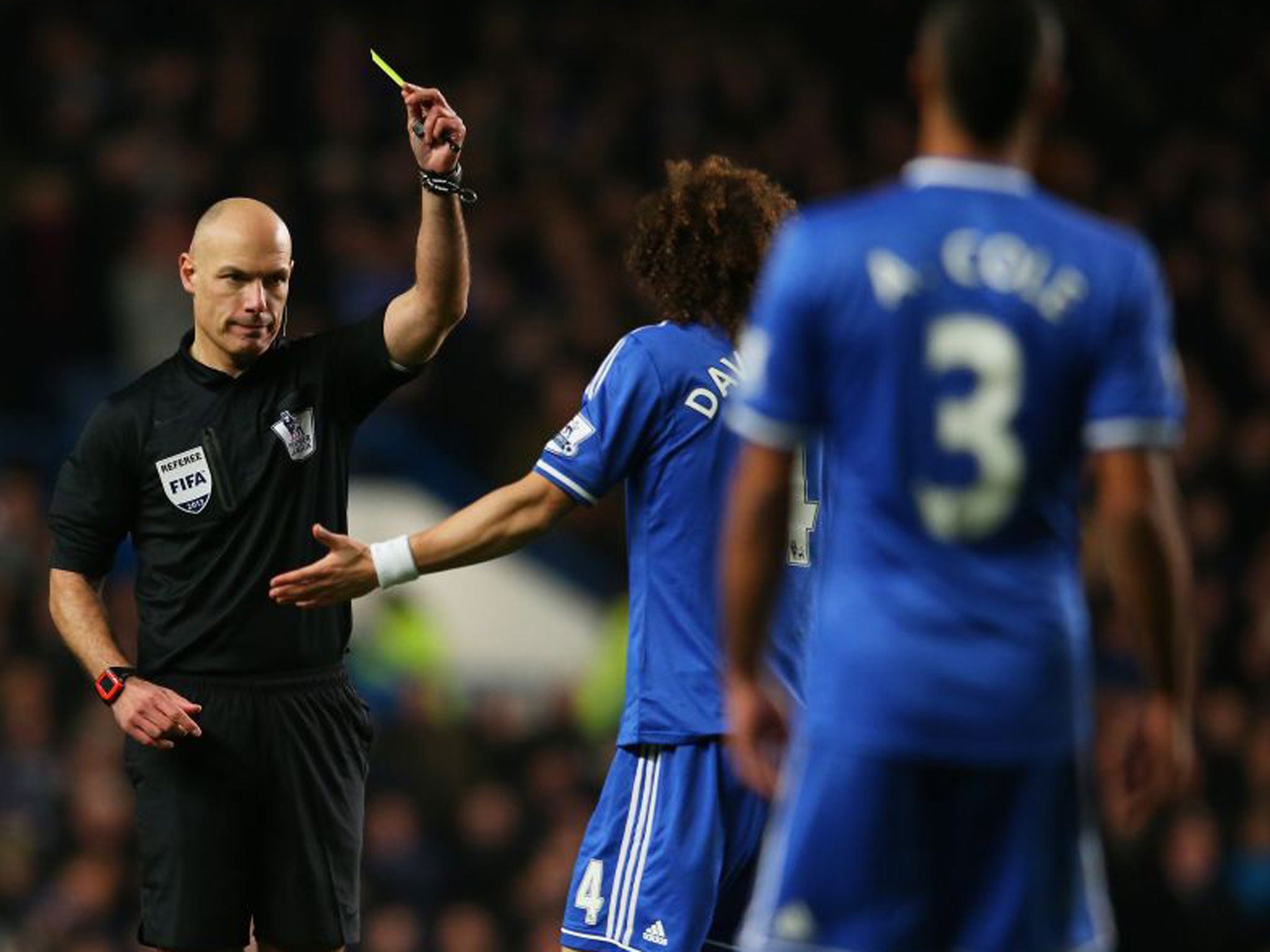 Referee Howard Webb (left) books David Luiz in Chelsea's 2-1 win over Liverpool on Sunday
