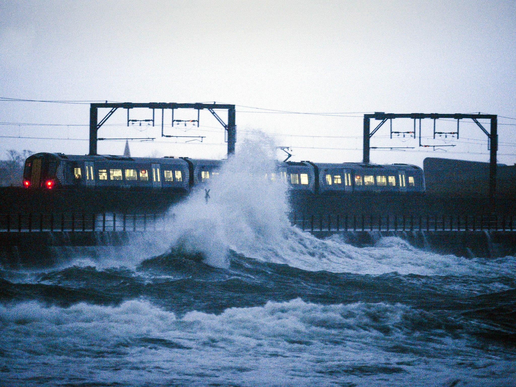 A train leaves Saltcoats station as a large wave crashes nearby on December 27, 2013 in Saltcoats, Scotland. Severe weather warnings have been issued for many parts of Scotland as the country is affected by gale force winds and heavy rain