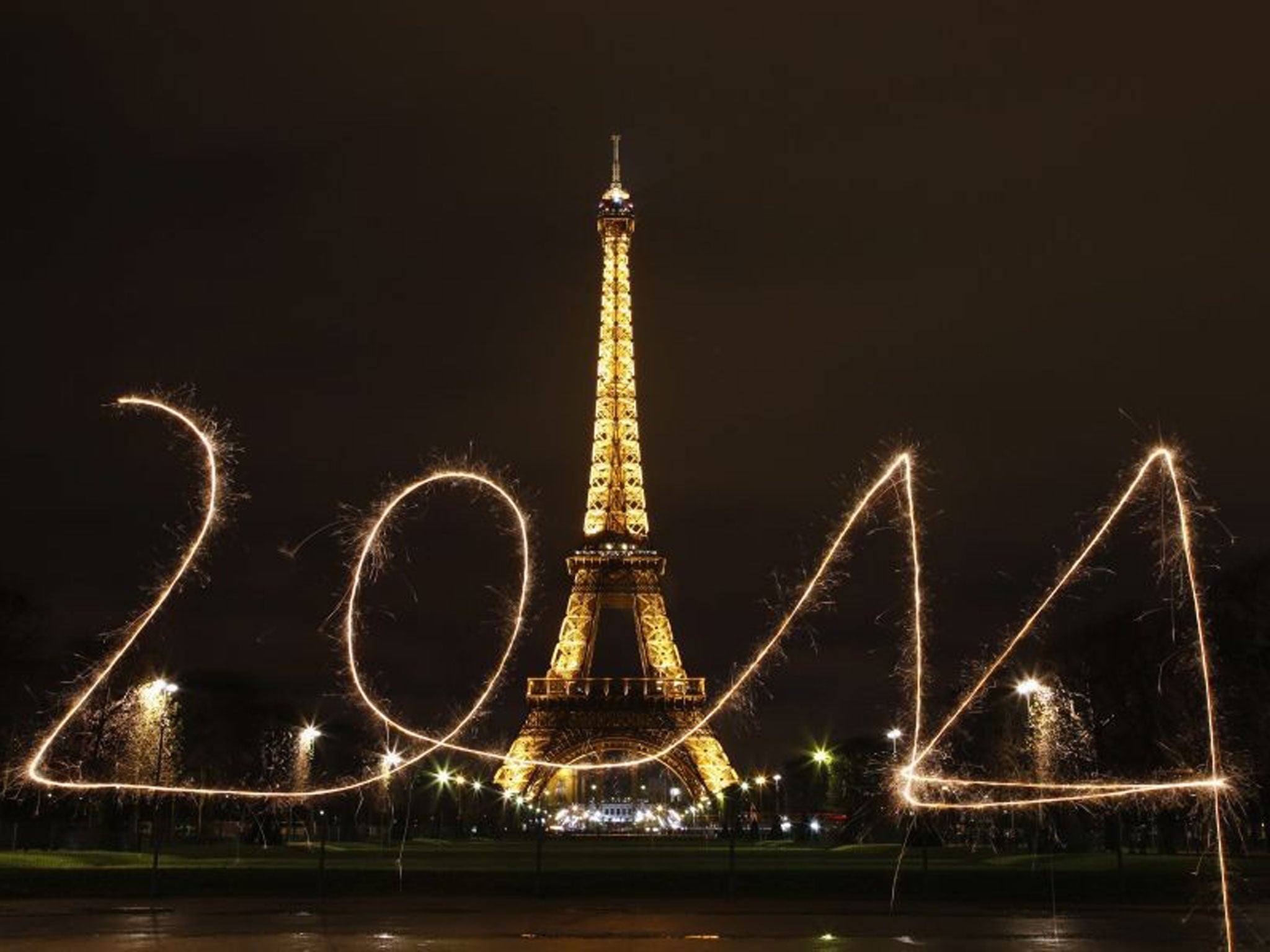 A reveller writes '2014' with sparklers ahead of New Year's Eve, in front of the Eiffel Tower in Paris
