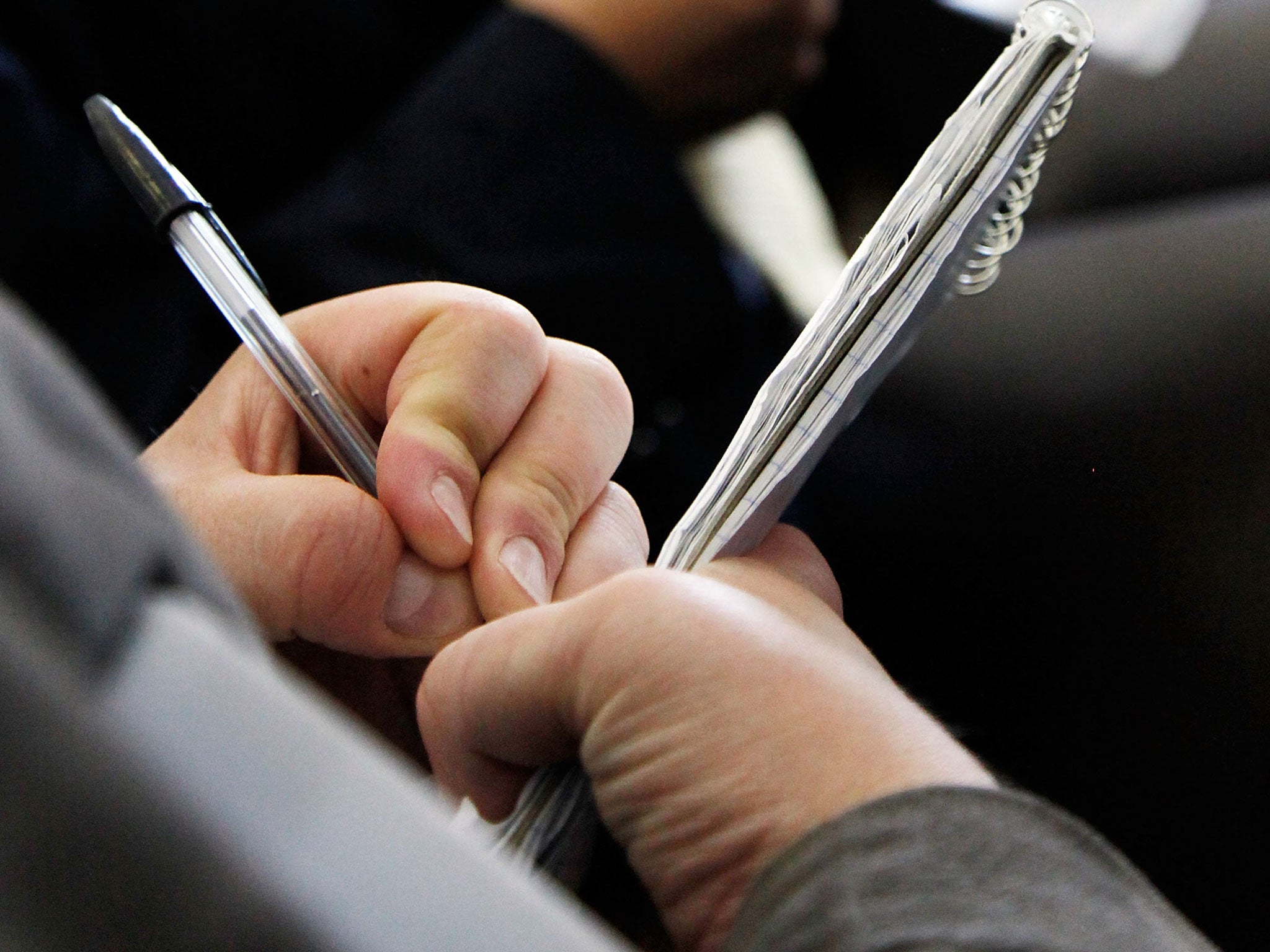 A reporter takes notes at a press conference.