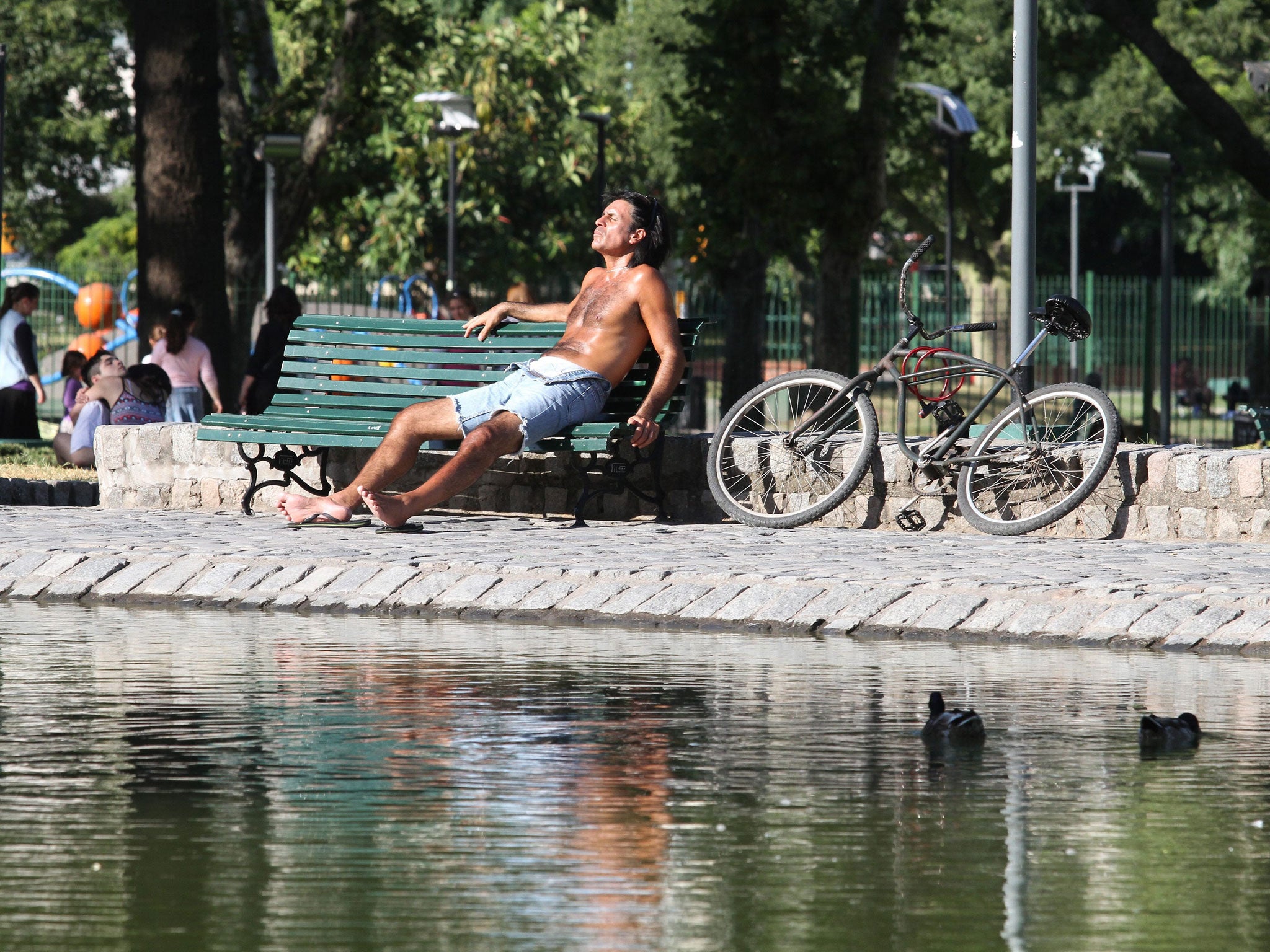 A man sits under the sun at the Centenario park in Buenos Aires, Argentina.