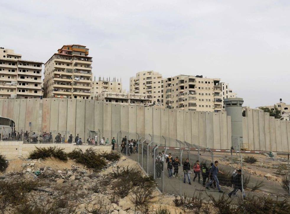 File: Palestinian children disembark their school bus and walk towards an Israeli checkpoint in East Jerusalem