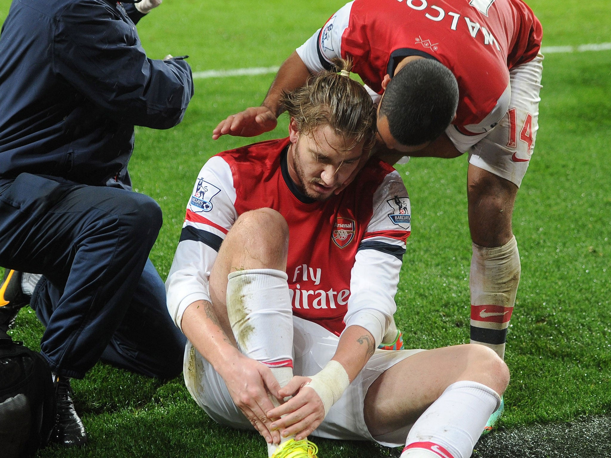 Nicklas Bendtner goes down holding his ankle after scoring and is consoled by Theo Walcott