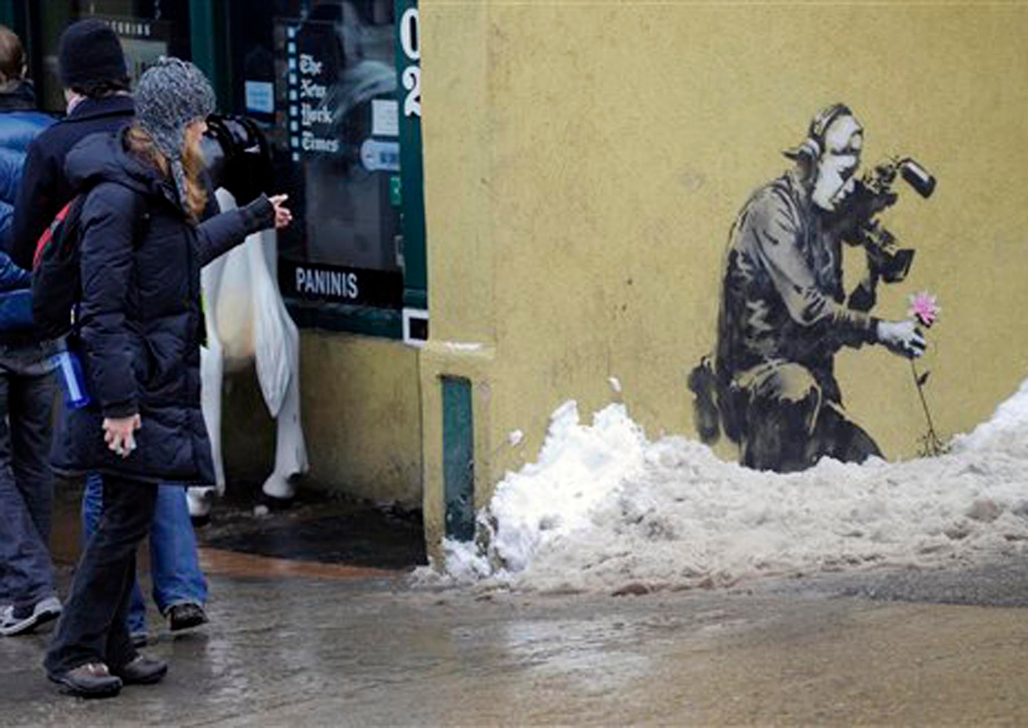 A pedestrian points at one of Banksy's artworks in Park City in Utah